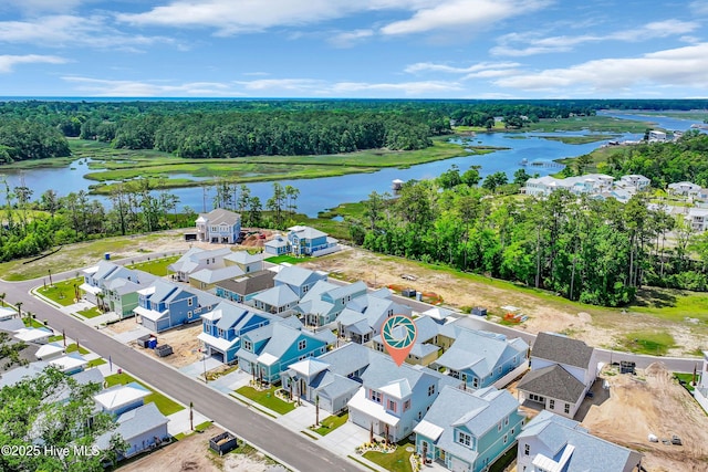 aerial perspective of suburban area featuring a large body of water and a tree filled landscape