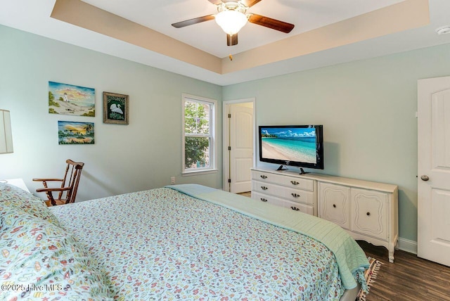 227 NE 38th St, Oak Island, NC 28465 - bedroom featuring dark wood-style floors, a ceiling fan, and a raised ceiling