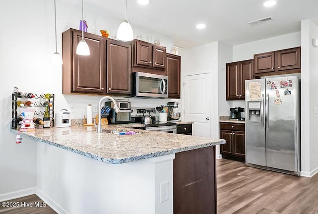 1807 St Patricks Ct SE Lot 267, Bolivia, NC 28422 - kitchen with appliances with stainless steel finishes, dark brown cabinetry, light wood-style flooring, a peninsula, and recessed lighting