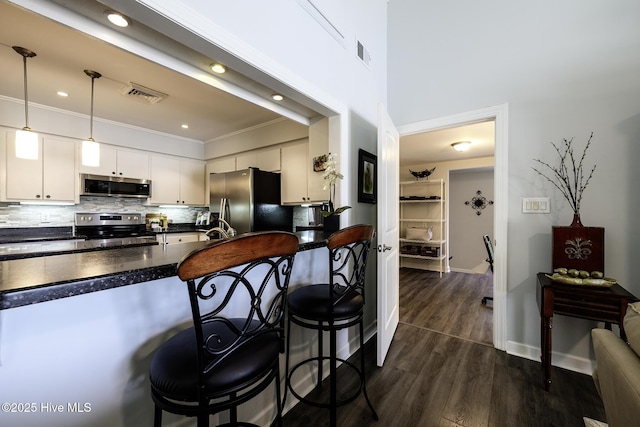 302 Plantation Dr, New Bern, NC 28562 - kitchen with appliances with stainless steel finishes, dark countertops, a kitchen breakfast bar, decorative backsplash, and white cabinetry