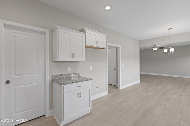 206 Ethan Pl, Hubert, NC 28539 - kitchen with light stone countertops, light wood-type flooring, white cabinetry, baseboards, and open floor plan