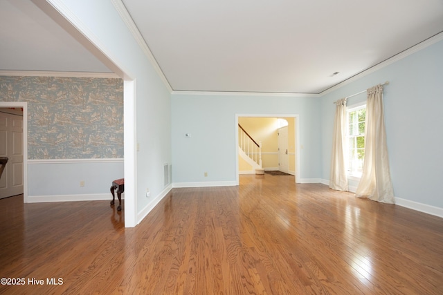 unfurnished room with ornamental molding, stairway, wood finished floors, baseboards, and arched walkways