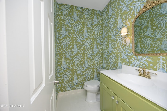 bathroom featuring wallpapered walls, tile patterned floors, toilet, vanity, and baseboards