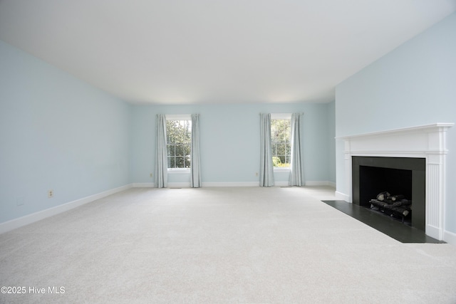 unfurnished living room featuring light colored carpet, healthy amount of natural light, and a fireplace with flush hearth