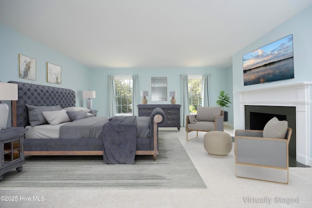 bedroom featuring multiple windows, a fireplace, and carpet flooring