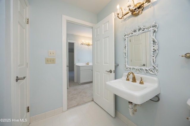 bathroom featuring baseboards, a sink, and a chandelier