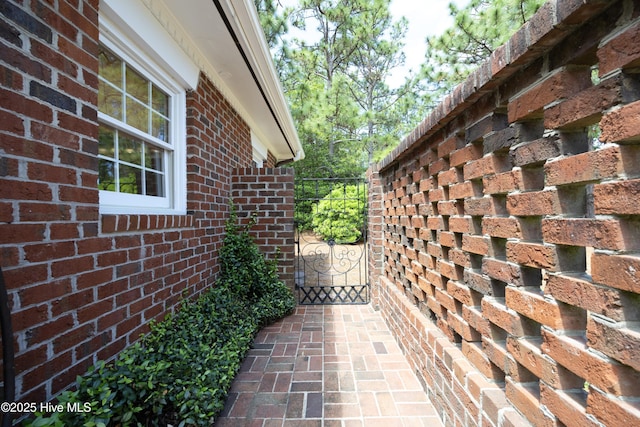 view of side of home with brick siding and a gate