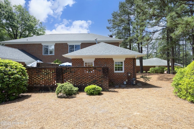 back of house with a shingled roof and brick siding