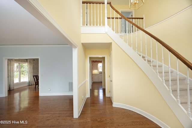 foyer with a towering ceiling, wood finished floors, stairway, a chandelier, and baseboards