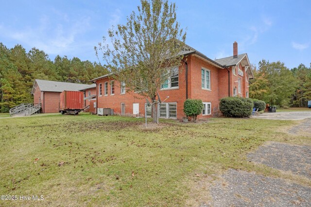 9291 NC-171, Williamston, NC 27892 - view of home's exterior with a chimney, brick siding, and a lawn