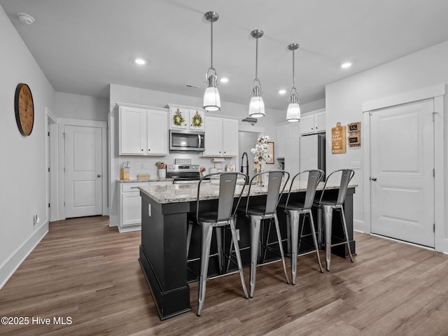 221 Salt Meadow Ln, Newport, NC 28570 - kitchen featuring stainless steel appliances, recessed lighting, a center island with sink, white cabinets, and wood finished floors