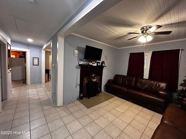 living area featuring light tile patterned flooring, a ceiling fan, attic access, and crown molding
