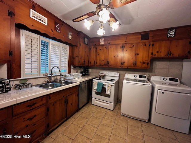kitchen featuring a sink, electric stove, dishwasher, washer and dryer, and a ceiling fan
