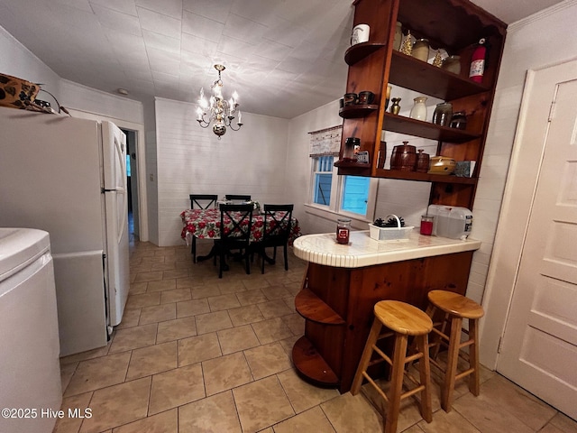 kitchen featuring open shelves, a chandelier, freestanding refrigerator, tile countertops, and light tile patterned floors