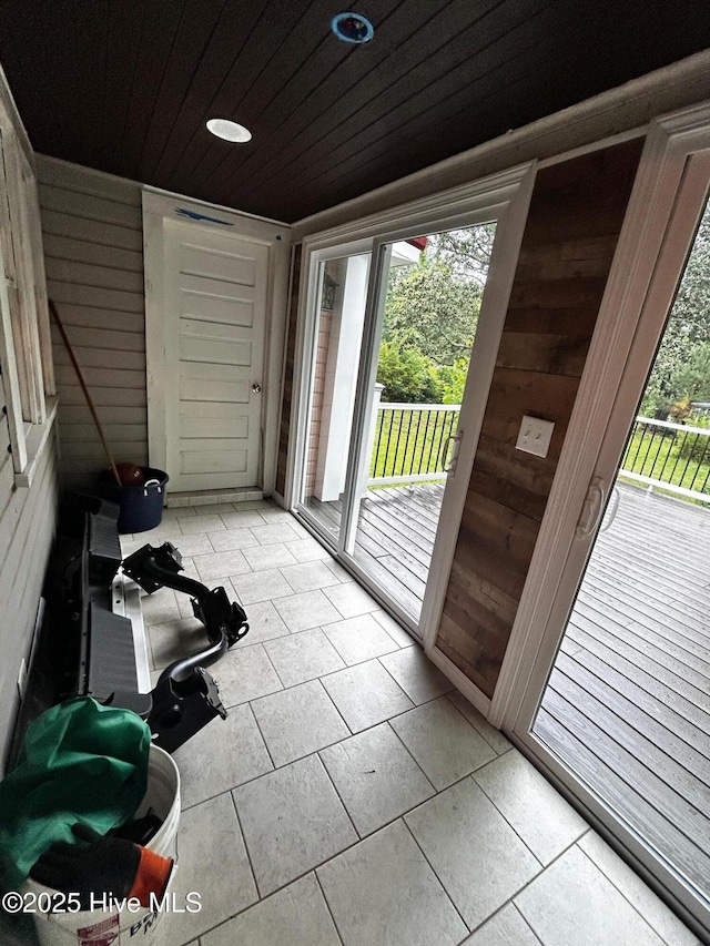 doorway featuring wood walls, plenty of natural light, light tile patterned floors, and wood ceiling