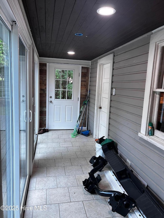 entryway with wood walls, wood ceiling, and light tile patterned floors