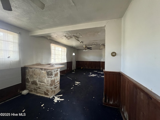 144 Shannonhouse Rd, Edenton, NC 27932 - miscellaneous room with a ceiling fan, a wainscoted wall, wood walls, a textured ceiling, and concrete flooring