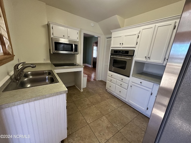 kitchen featuring appliances with stainless steel finishes, a sink, white cabinets, dark tile patterned floors, and light countertops