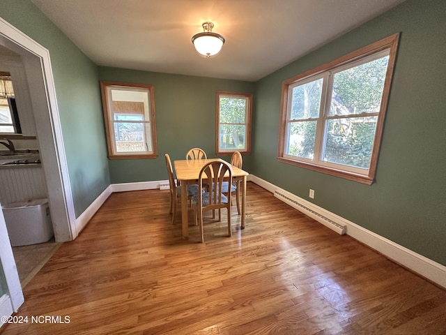 dining space featuring baseboard heating, light wood-type flooring, and baseboards