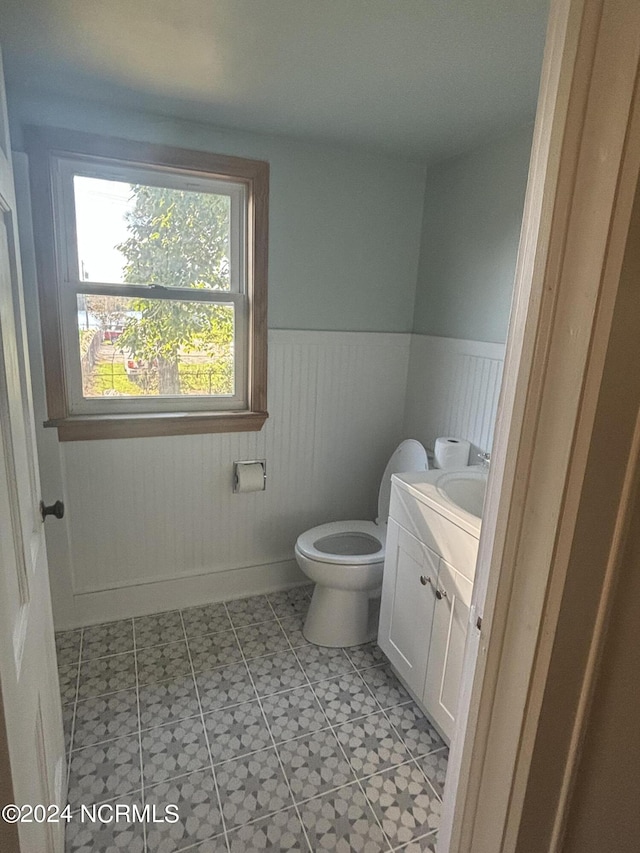 bathroom with wainscoting, vanity, toilet, and baseboards