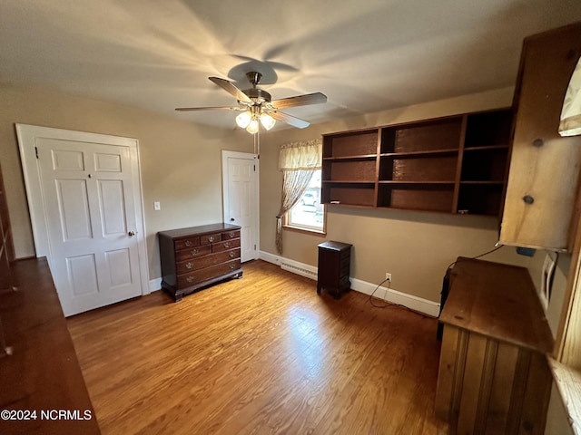 unfurnished bedroom with baseboards, light wood finished floors, a baseboard heating unit, and ceiling fan