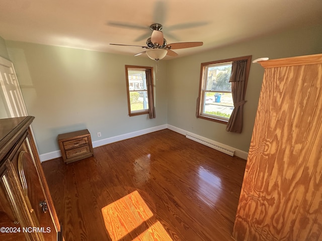 unfurnished bedroom featuring a baseboard radiator, multiple windows, baseboards, and dark wood-style floors