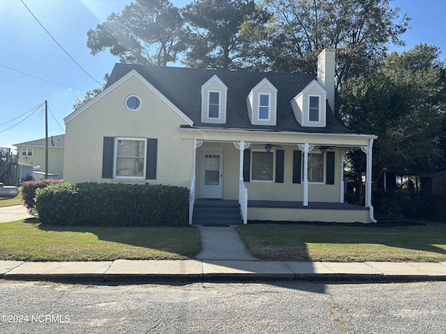 view of front facade featuring covered porch, a chimney, a front lawn, and brick siding