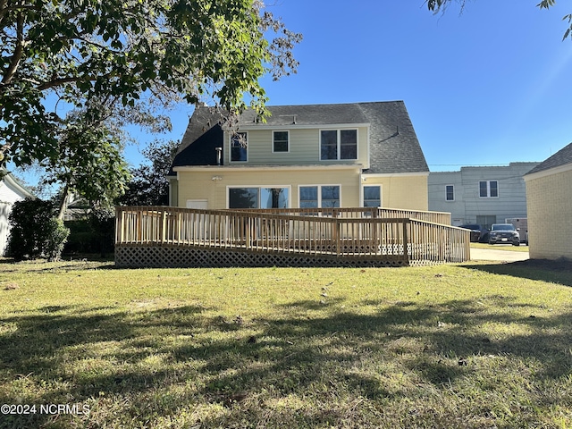 back of house featuring a wooden deck, a lawn, and roof with shingles