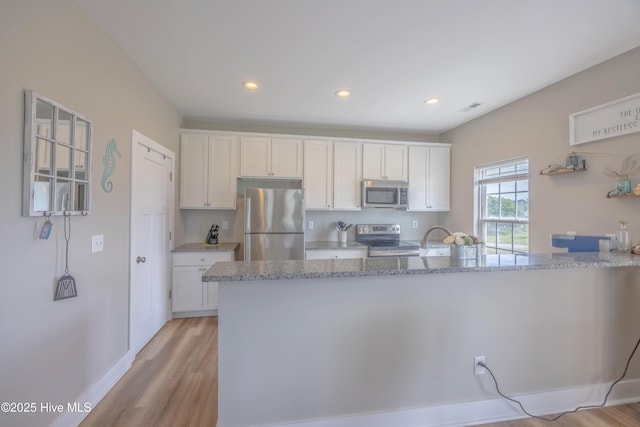 200 Twin Oaks Dr Unit B, Hampstead, NC 28443 - kitchen with stainless steel appliances, light wood-type flooring, white cabinets, light stone countertops, and recessed lighting