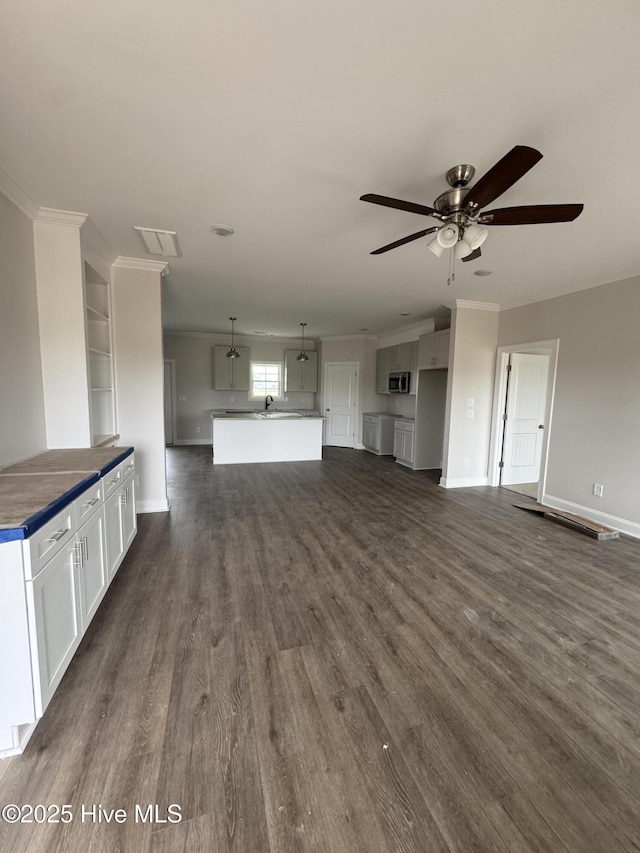 unfurnished living room with ornamental molding, ceiling fan, dark wood-style flooring, and baseboards