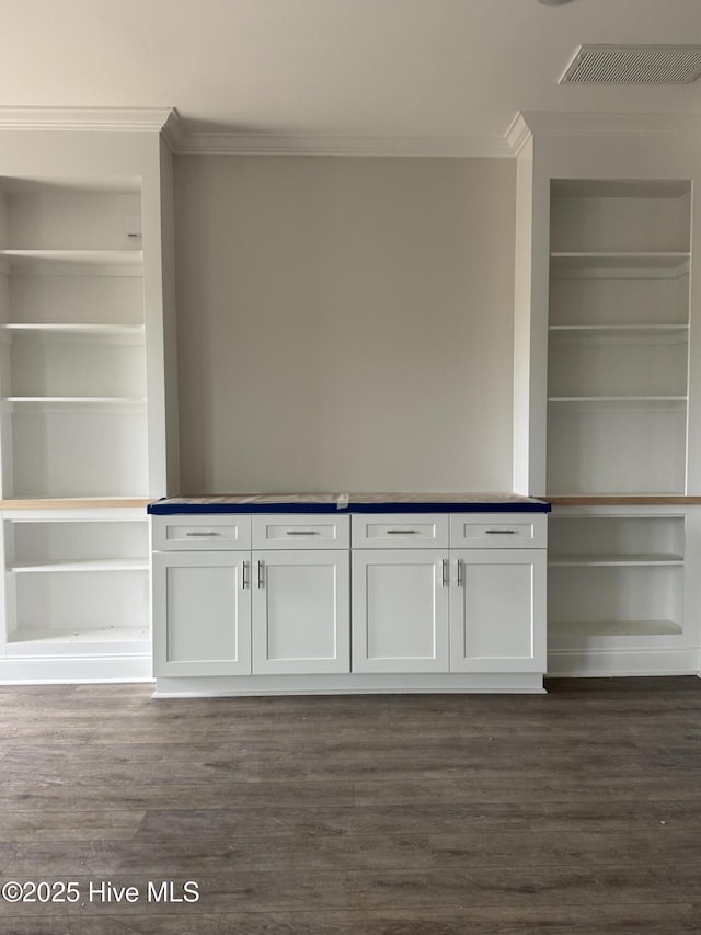 interior space with ornamental molding, built in features, and dark wood-style flooring