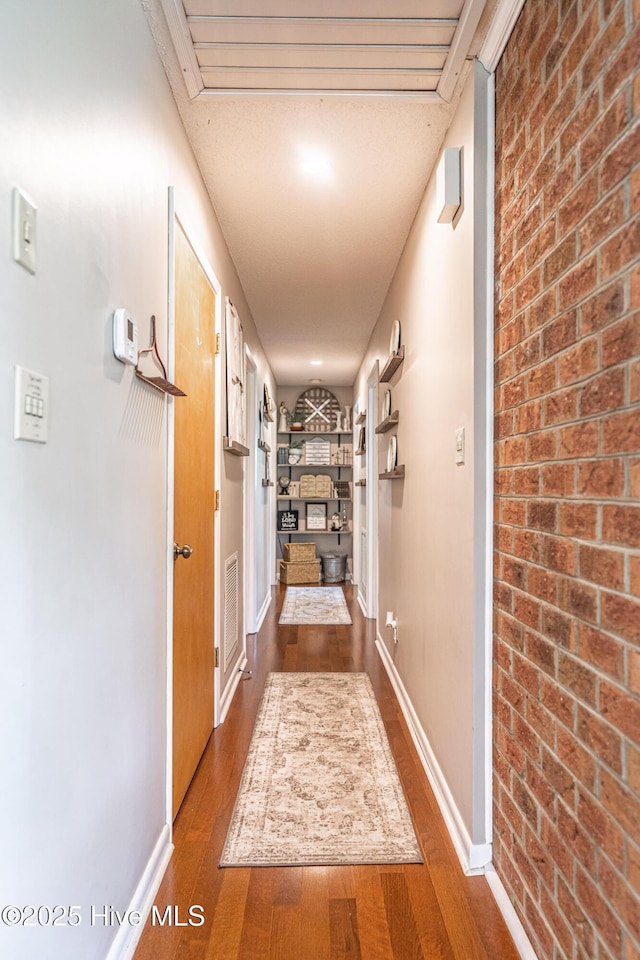 118 Lancashire Ln, West End, NC 27376 - hallway featuring dark wood-type flooring, brick wall, and baseboards