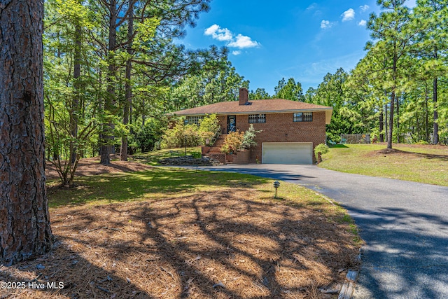 118 Lancashire Ln, West End, NC 27376 - view of front of house with brick siding, a chimney, asphalt driveway, a garage, and stairs
