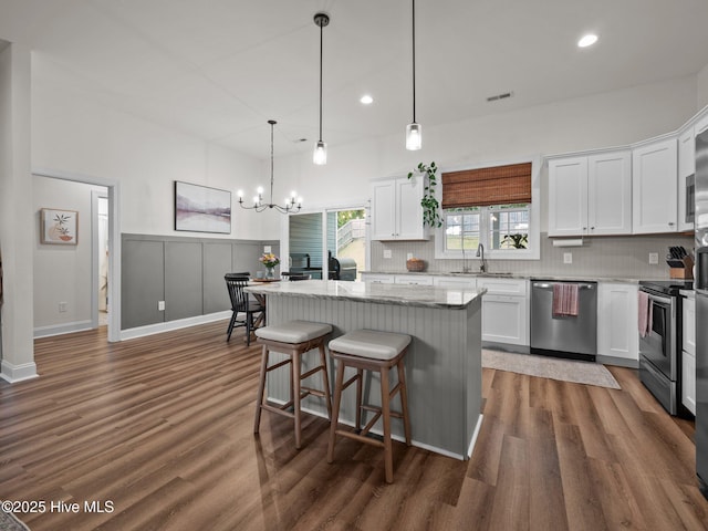 kitchen featuring stainless steel appliances, a sink, decorative backsplash, dark wood-type flooring, and white cabinetry