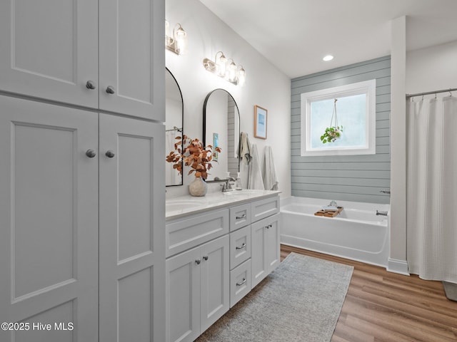 bathroom with a bath, wood finished floors, double vanity, recessed lighting, and a shower with curtain