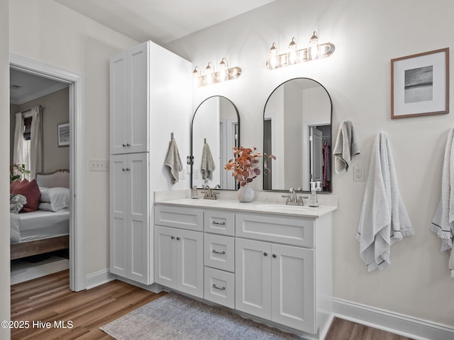 full bath with wood finished floors, double vanity, baseboards, and ensuite bath