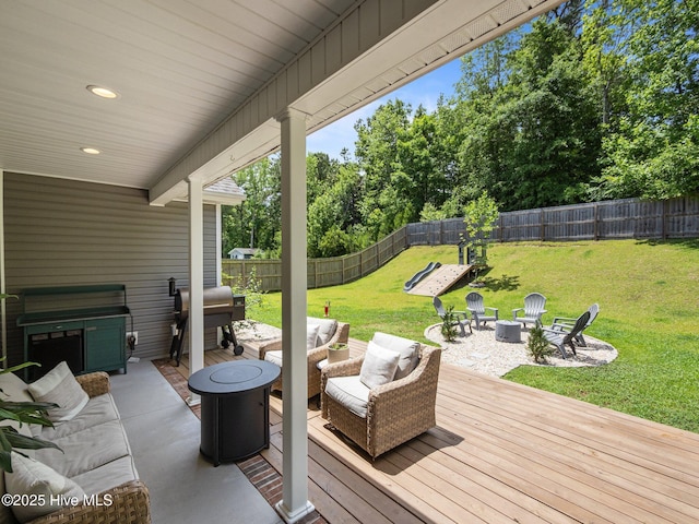 deck featuring area for grilling, an outdoor living space with a fire pit, and view of wooded area