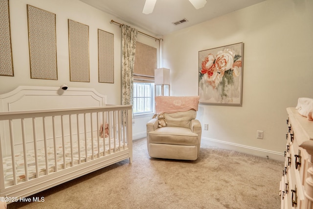 carpeted bedroom featuring baseboards, a nursery area, and a ceiling fan