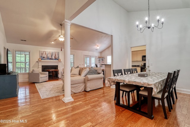 dining space with light wood-style flooring, a chandelier, a glass covered fireplace, ceiling fan, and baseboards