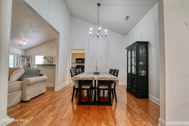 dining area with light wood-style flooring, baseboards, a chandelier, and high vaulted ceiling