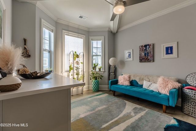 living area featuring wood finished floors, baseboards, and crown molding