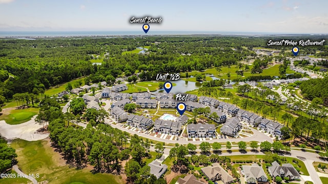 bird's eye view of a local golf course, a nearby body of water, and a heavily wooded area