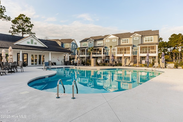 community pool featuring fence, a patio area, and a residential view