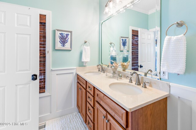 104 SE 32nd St, Oak Island, NC 28465 - bathroom featuring wainscoting, a decorative wall, double vanity, and crown molding