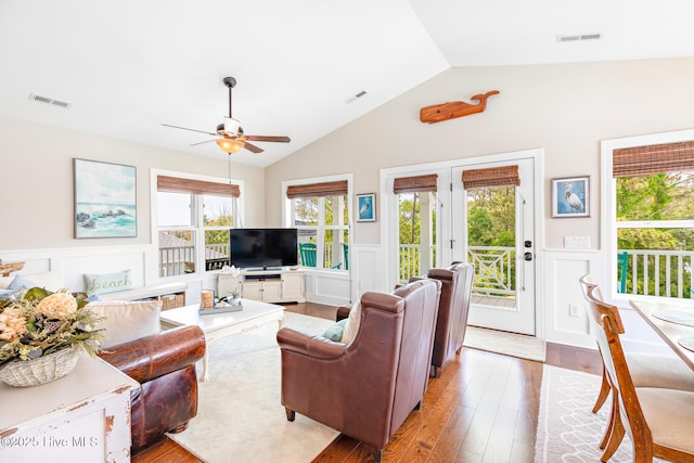 104 SE 32nd St, Oak Island, NC 28465 - living area featuring a decorative wall, a wainscoted wall, ceiling fan, vaulted ceiling, and wood finished floors