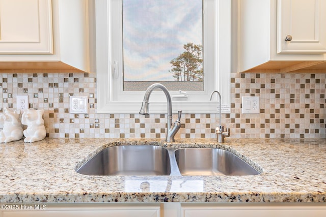104 SE 32nd St, Oak Island, NC 28465 - kitchen view of a sink, white cabinets, light stone counters, and backsplash