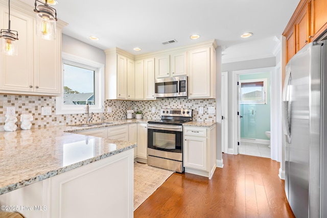 104 SE 32nd St, Oak Island, NC 28465 - kitchen featuring stainless steel appliances, light stone counters, light wood finished floors, a sink, and tasteful backsplash