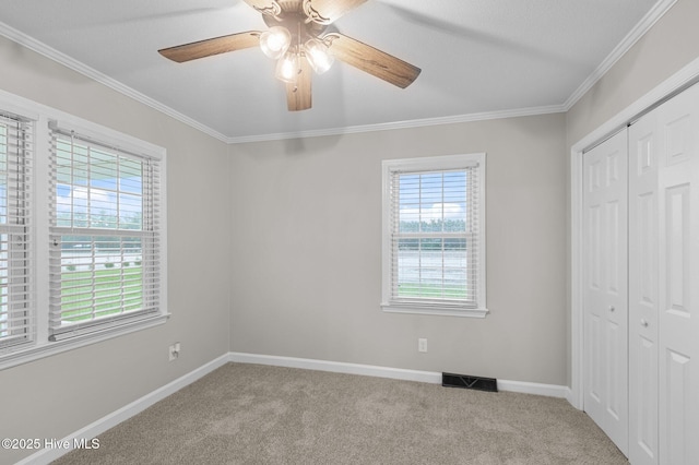 unfurnished bedroom featuring multiple windows, carpet floors, a closet, and ornamental molding
