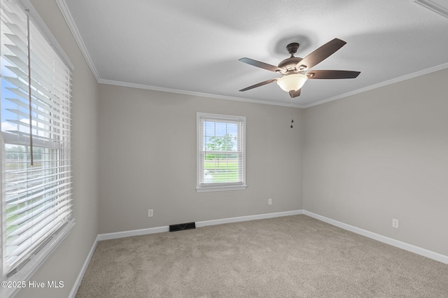 empty room featuring carpet floors, ornamental molding, baseboards, and ceiling fan