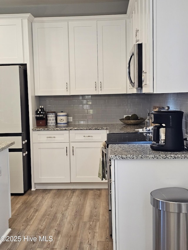 568 Transom Way, Sneads Ferry, NC 28460 - kitchen with freestanding refrigerator, white cabinetry, light wood-style flooring, and decorative backsplash